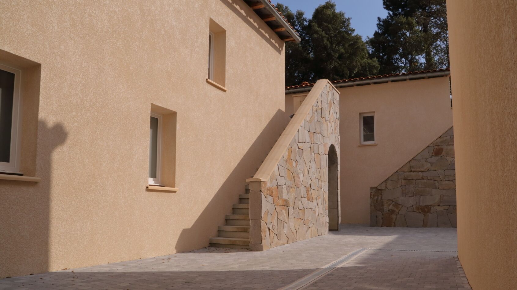 A building with a stone staircase leading to an upper level, a small window, and a stone wall.