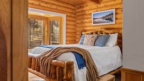 A wooden cabin interior with a bed, a window with blinds, and a framed picture on the wall. - Bear Kub Kabin + Games + 1 Block to Snow Summit! (Big Bear Lake)