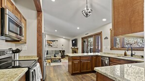 Una cocina moderna con encimeras de granito, electrodomésticos de acero inoxidable, armarios de madera y una isla central.
