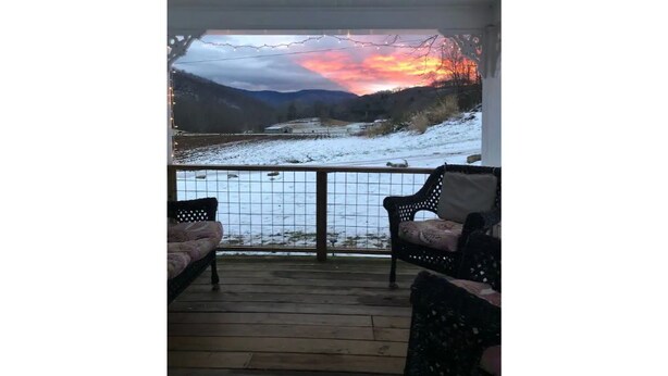 En overdækket veranda med udsigt over et snelandskab og en solnedgang.