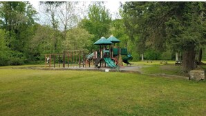 Ein Spielplatz mit Rutsche, Klettergerüsten und einem überdachten Sitzbereich.