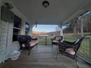 Relax on the covered porch with two comfortable chairs and a scenic view of the surrounding landscape and distant mountains.