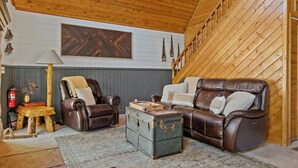 A cozy living room with a brown leather sofa, a wooden coffee table, and a fireplace.