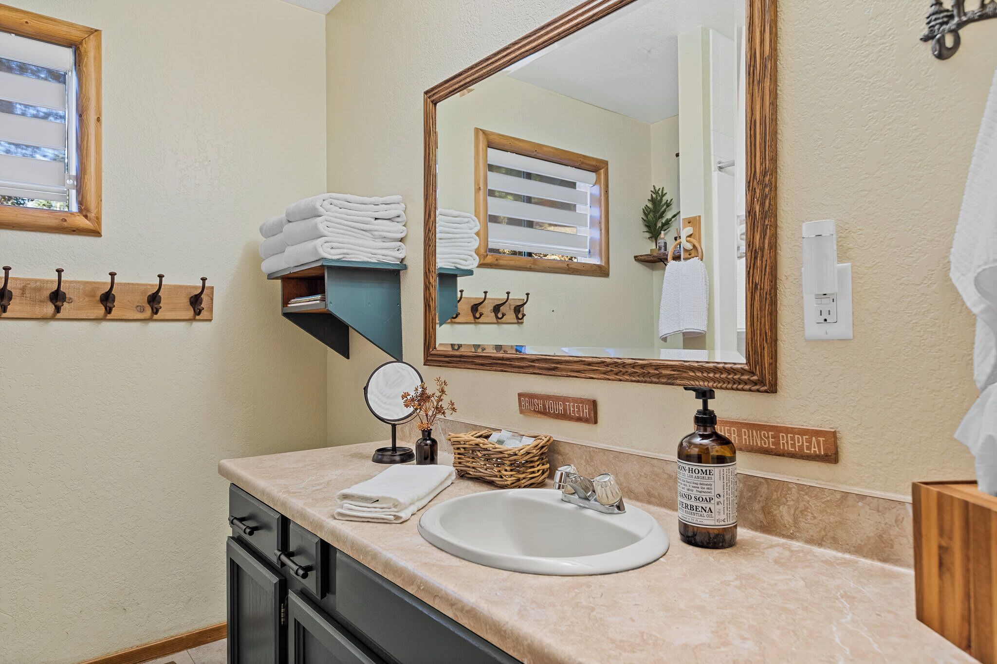 A bathroom with a sink, mirror, towel rack, and a soap dispenser.