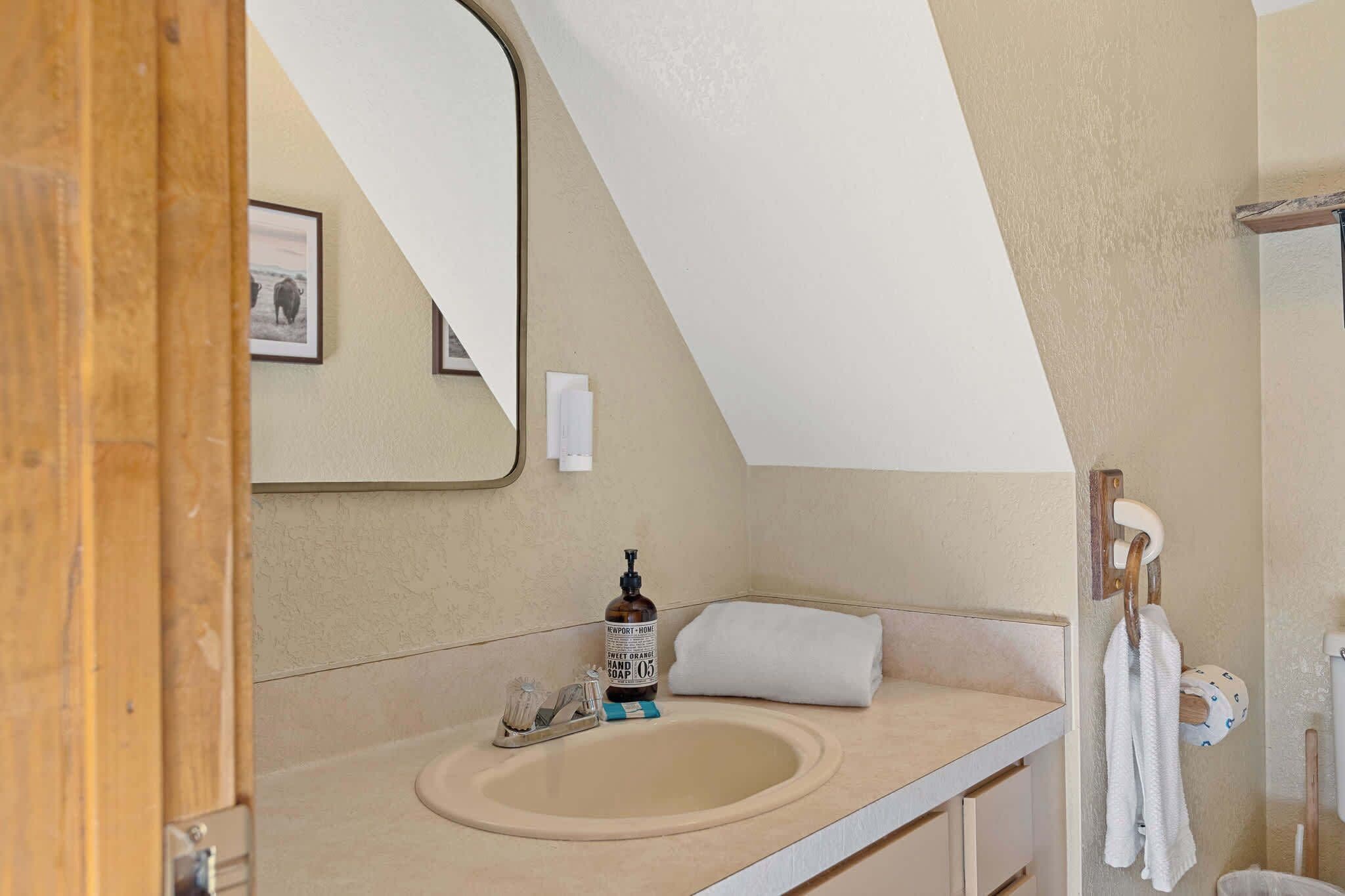 A bathroom with a sink, a mirror, a towel rack, and a picture on the wall.