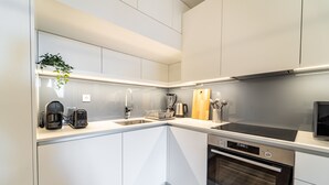 Una cocina moderna con armarios blancos, horno empotrado, cafetera y tostadora.