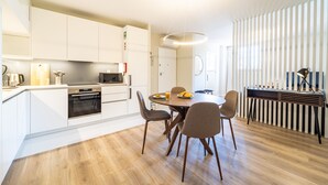 Una cocina moderna con armarios blancos, una mesa de comedor con sillas y un horno empotrado.