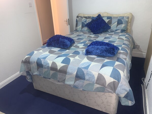 Una cama con una colcha de estampado geométrico y dos almohadas azules.