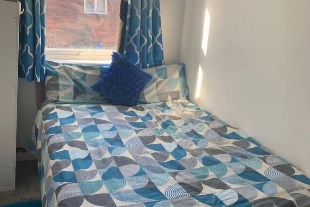 A bedroom with a bed, curtains, and a view of the outside.