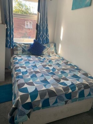 Un dormitorio con cama, cortinas y vistas al exterior.