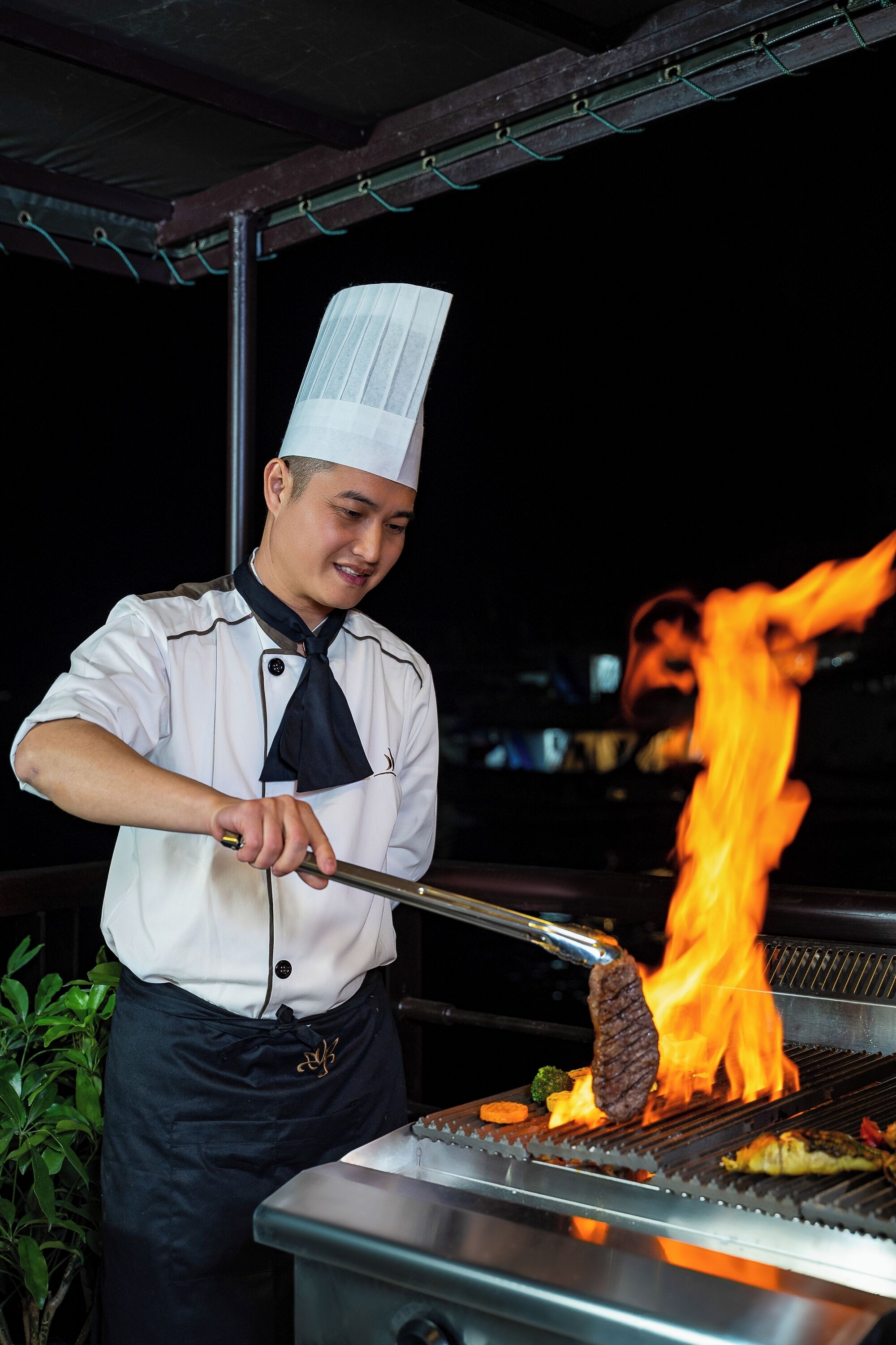 A chef grilling meat over an open flame.