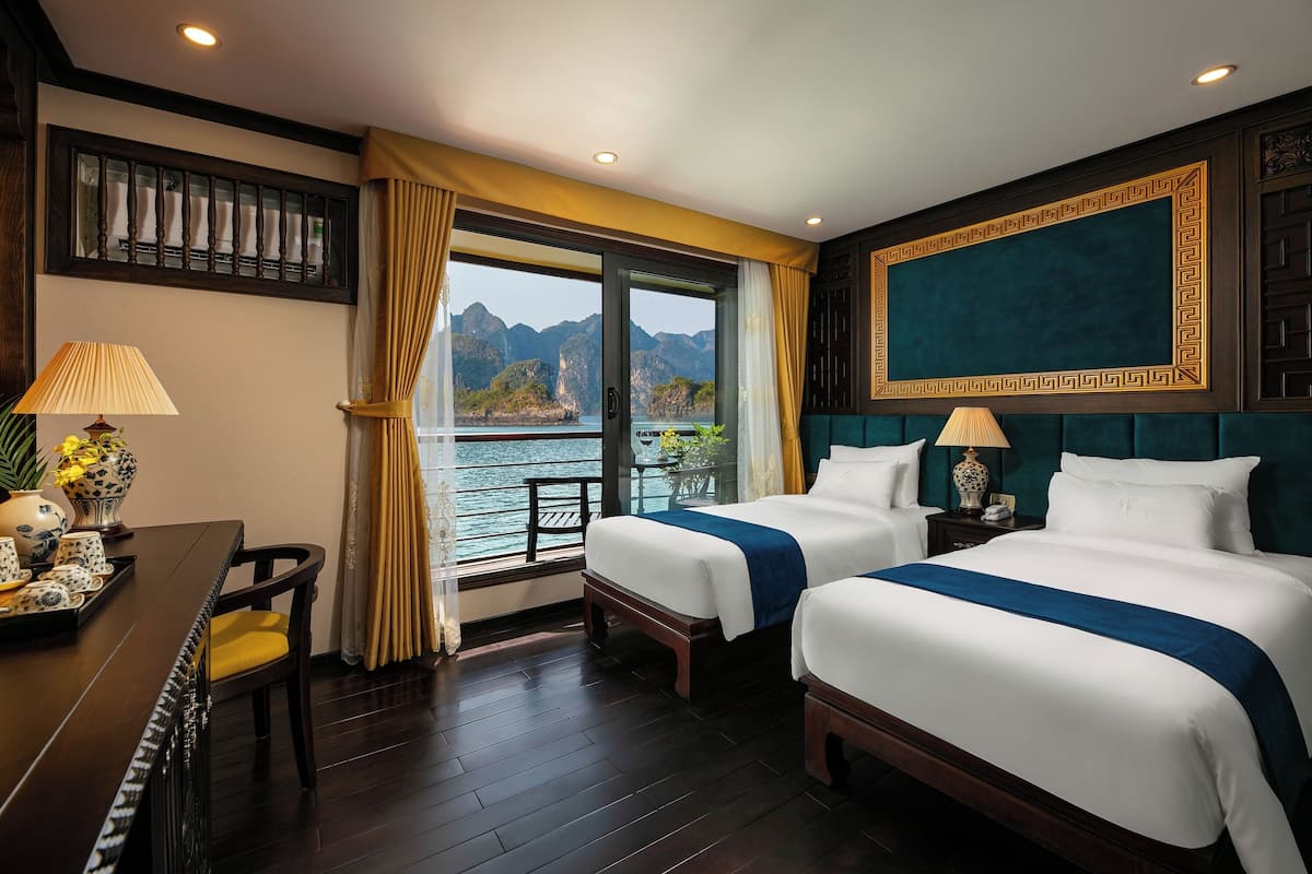A hotel room with two beds, a dining table, and a view of the water.