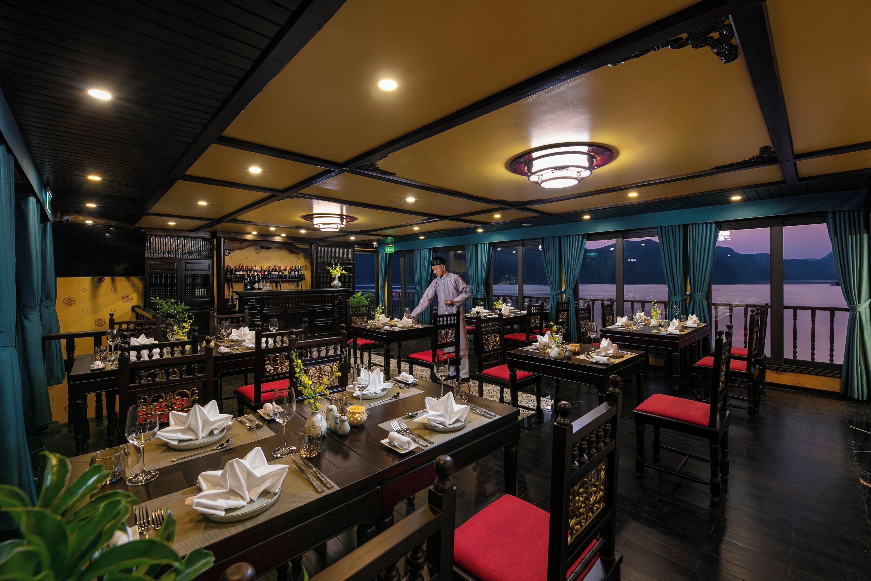 A restaurant with tables set for dining, a bar area, and a view of the water.