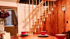 A dining area with wooden flooring, a staircase with exposed beams, and a wooden wall. - Muskie-Lounge River Retreat! Secluded getaway.  (Buckhannon)