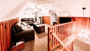 A loft-style living area with a high ceiling, a wooden staircase, and a cozy seating arrangement. - Muskie-Lounge River Retreat! Secluded getaway.  (Buckhannon)
