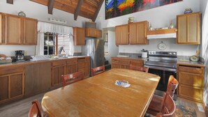 Una cucina con mobili in legno, un frigorifero in acciaio inossidabile, un fornello e un tavolo da pranzo con sedie.