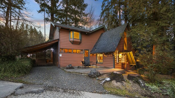 Un rustico chalet con tetto spiovente, un portico coperto e un vialetto sterrato.