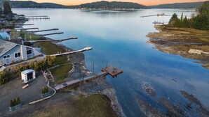 En fastighet vid sjön med en brygga, ett litet hus och en båt.