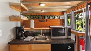 A compact kitchen with a sink, a coffee maker, a microwave, and wooden cabinets. - Cabin #5 (Union)