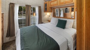 Un dormitorio con una cama grande, armarios de madera, una mesita de noche y una ventana con cortinas.