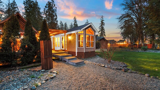 A lodge with a wooden exterior, large windows, and a gravel driveway. - Hot Tub Cabin #8 with Fire Pit (Union)