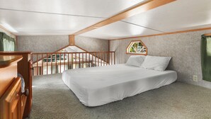 A bedroom with a bed, a wooden dresser, a window, and a balcony. - Hot Tub Cabin #8 with Fire Pit (Union)