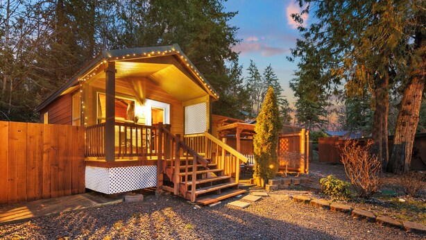 Eine Holzhütte mit Veranda, Treppe und einer kleinen Terrassenfläche.