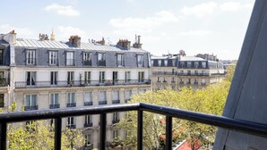 A row of multi-story buildings with balconies, a clear sky, and some greenery. - Alberte Hotel (Paris)