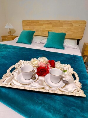 Una cama bien hecha con una colcha azul, dos almohadas color turquesa y un cabecero de madera.