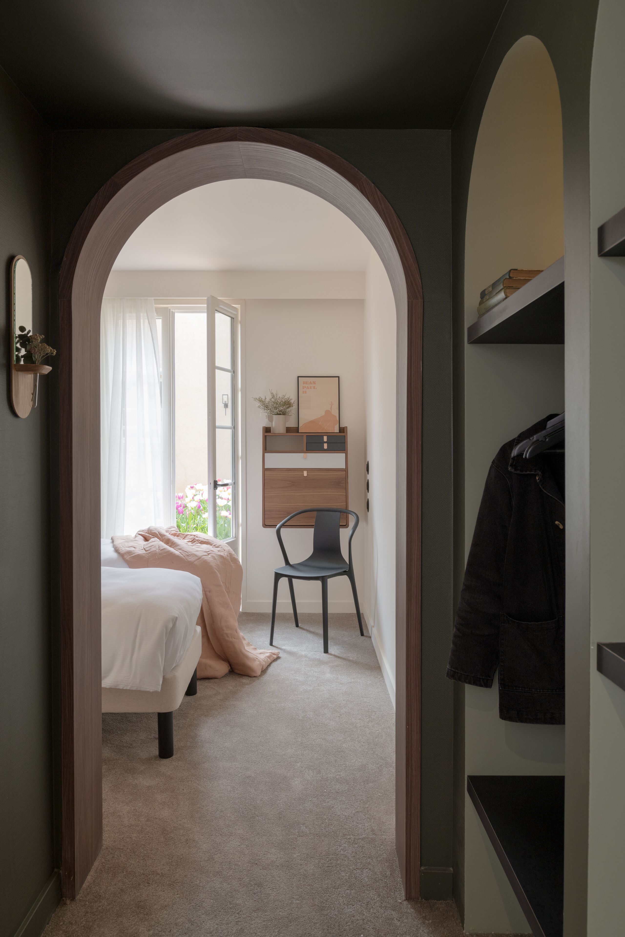 Un dormitorio con cama, una silla, un escritorio y un armario.