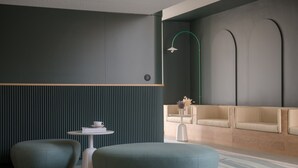 Un espacio lounge moderno con una pared verde oscuro, un sofá beige y dos zonas de estar circulares.