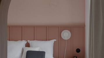 A bedroom with a bed, bedside table, and a wall-mounted fan.