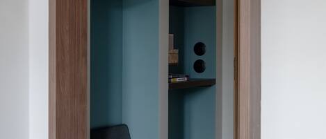 A room with a wooden arched doorway leading to a blue alcove with shelves and a black chair.