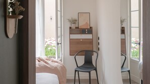 Un dormitorio con cama, una silla, un aparador y un espejo.