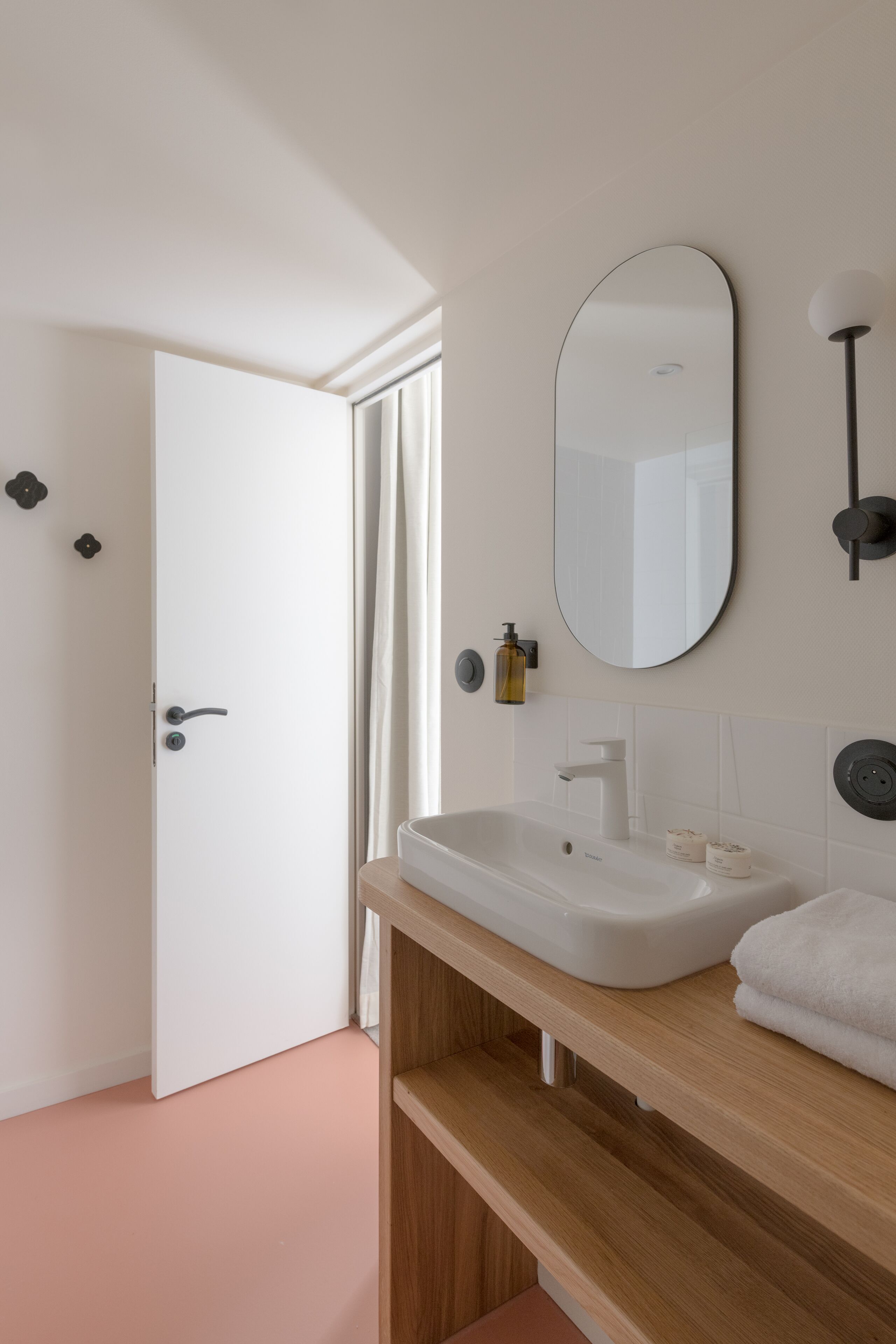 A modern bathroom with a white sink, mirror, and wooden vanity.
