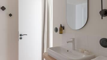 A modern bathroom with a white sink, mirror, and wooden vanity.