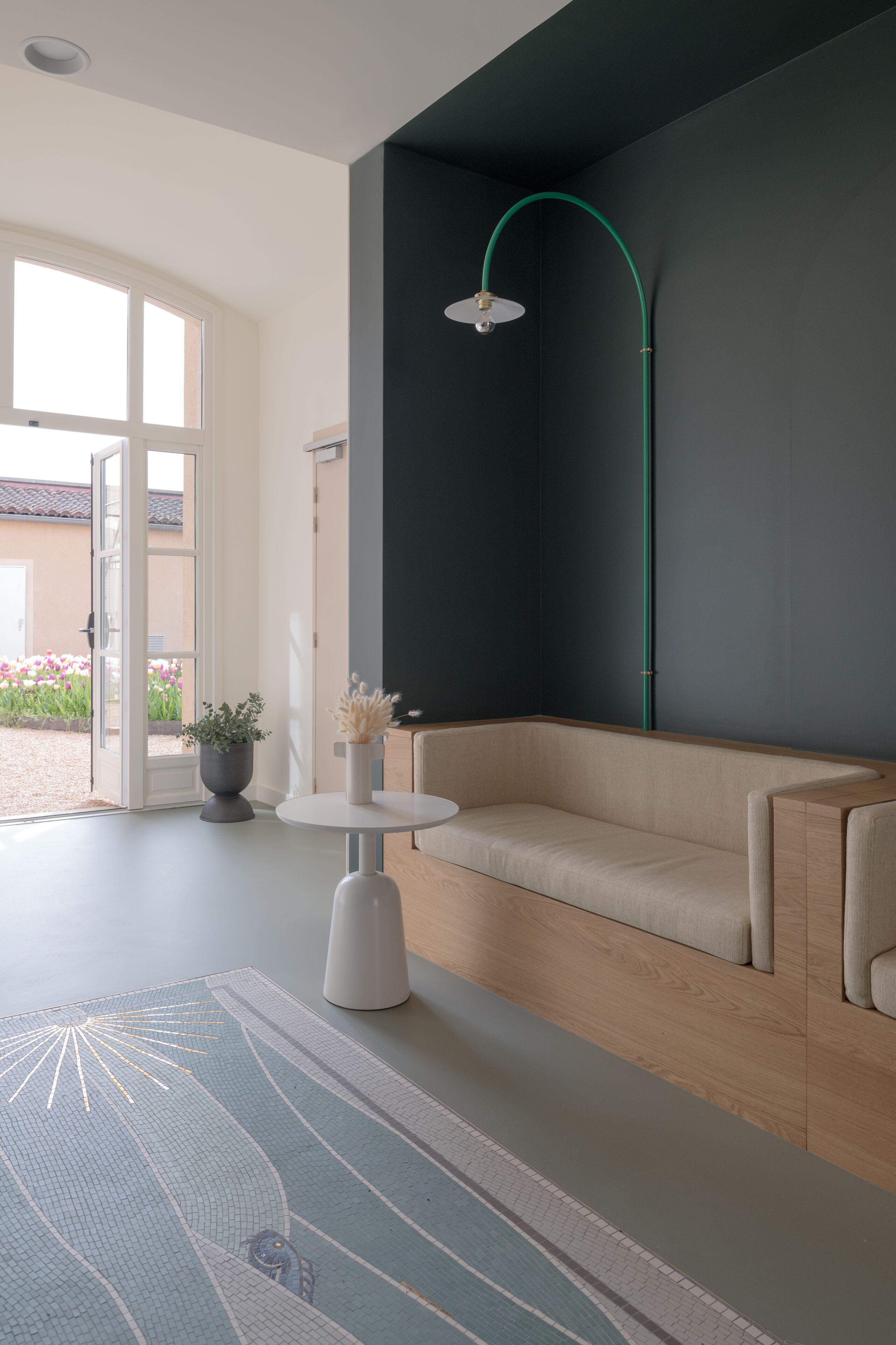 A modern living room with a beige sofa, a round white table, and a green floor lamp.