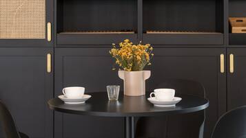 A black dining area with two chairs, a table, and a shelf with glassware and bottles.