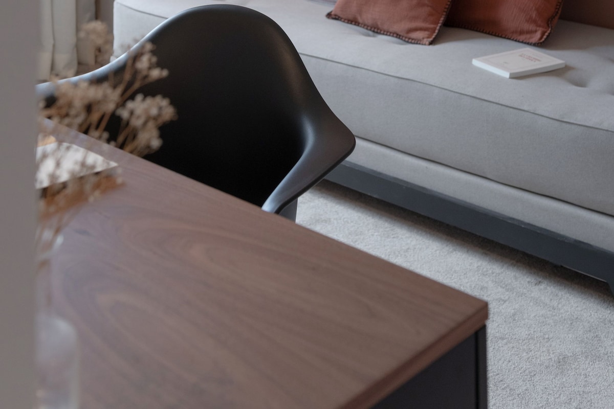 A modern hotel room with a bed, bedside table, lamp, and a wall-mounted shelf.