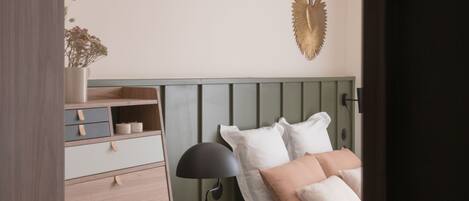 Un dormitorio con cama, mesita de noche, cómoda y un adorno en la pared.