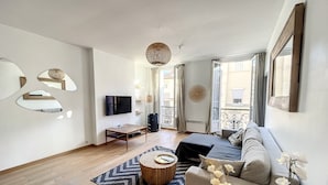 Una sala de estar moderna con sofá, mesa de centro, televisor y espejos decorativos.