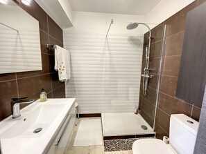Une salle de bain moderne avec une baignoire, une douche, des toilettes et un grand miroir.