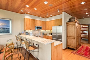 A modern kitchen with wooden cabinets, stainless steel appliances, and a granite countertop.