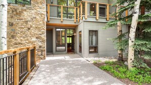 A two-story building with a stone facade, wooden balcony railings, and a covered entryway.