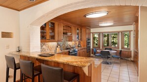 A kitchen with a granite countertop, wooden cabinets, a built-in oven, and a dining area with a table and chairs.