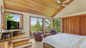 A bedroom with a large bed, a TV on a wooden shelf, and a balcony with a view of trees and mountains. - Sweeping down-valley views and comfortable upgrades. (Snowmass Village)