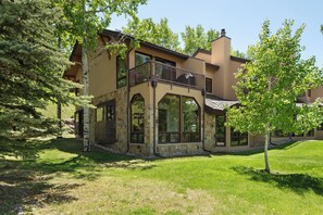 A two-story house with a balcony, large windows, and a stone facade. - Sweeping down-valley views and comfortable upgrades. (Snowmass Village)