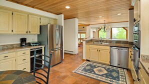 A spacious kitchen with wooden ceiling beams, stainless steel appliances, and a large island with a sink. - Sweeping down-valley views and comfortable upgrades. (Snowmass Village)