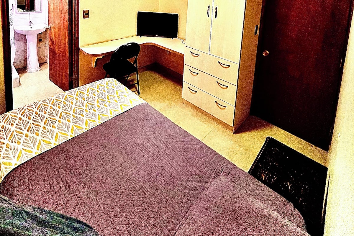 A hotel room with a bed, a desk, a wardrobe, and a bathroom.