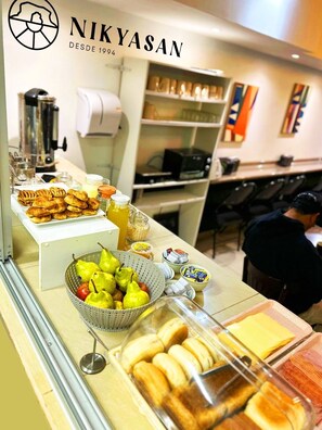 A buffet area with pastries, fruits, and beverages. - Hotel Nikyasan (Antofagasta)